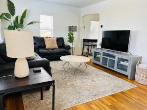 a living room with a black couch and a tv at Home Sweet Idahome, feels like home with all the decor you wish you could afford King bed in master, fully fenced dog friendly yard, a few blocks from BSU and downtown Boise, Your perfect stay! in Boise