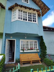 a blue house with a bench in front of it at Quarto de solteiro/casais in Teresópolis