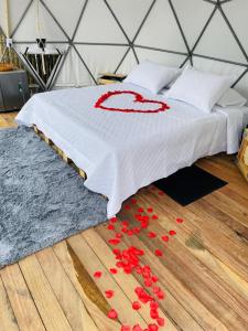 a bed with red flowers on a wooden floor at Drora glamping in Pereira