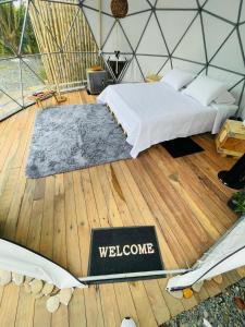 a bedroom with a bed with a welcome sign on the floor at Drora glamping in Pereira