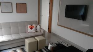 a living room with a white couch and a television at Aconchego no centro de Poços! in Poços de Caldas