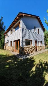 a large white house with a stone wall at Casa Catedral Bariloche in San Carlos de Bariloche