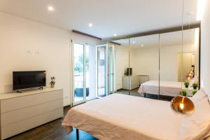 1 dormitorio con 2 camas, TV y espejo en Rosina Apartment surfing bed&vacation, en Terrasini