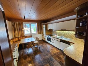 eine Küche mit weißen Schränken und einem Tisch darin in der Unterkunft Ferienwohnung Singer in Völs