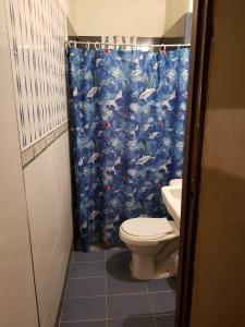 a bathroom with a toilet and a blue shower curtain at Cabaña en la playa Punta Bolivar in San Antero