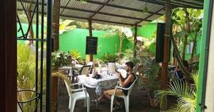 un hombre sentado en una mesa en un jardín en Cocos Hostel en Moyogalpa