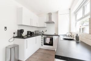 a kitchen with white cabinets and a black counter top at Home from Home - 5 mins from town! in Liverpool