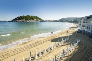 a beach with people walking on the sand and the water at Paradise Luxurious flat, free parking, 3 double rooms, terrace, jacuzzi, fully renovated in San Sebastián