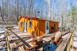 une cabine avec deux chaises sur une terrasse en bois dans l'établissement Hot Tub, Huge Deck, Lake, & FirePit at Cozy Cabin, à Lost City