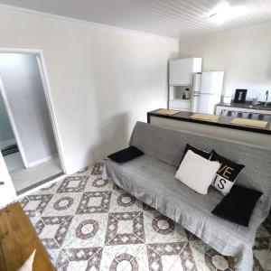 een woonkamer met een grijze bank en een keuken bij Lopes House Araçatiba in Praia de Araçatiba