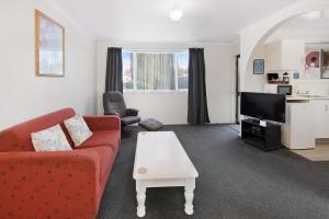 a living room with a red couch and a tv at ASURE Oakleigh Motel in Gore