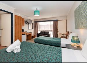 Habitación de hotel con 2 camas y sala de estar. en Winsor Park Motor Inn en Albury