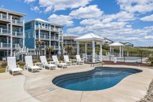 a patio with chairs and a swimming pool in front of a building at Poseidon in Atlantic Beach