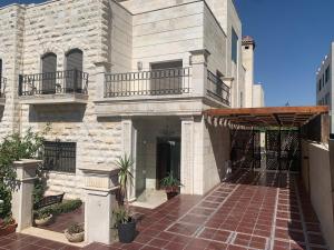 a large white building with a balcony and a brick walkway at Luxurious 3 Bedroom Villa in Abdoun-Amman in Amman