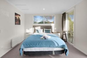 - une chambre avec un lit et une couverture bleue dans l'établissement ASURE Oakleigh Motel, à Gore