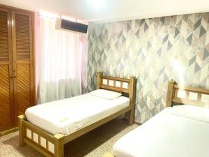 a bedroom with two beds and a wall at Sweet Home RIOHACHA in Ríohacha