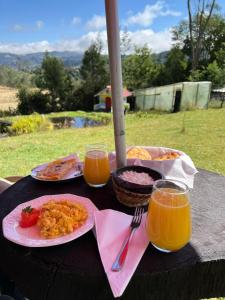 una mesa con platos de comida y dos vasos de zumo de naranja en Fantasia Glamping, en Bogotá