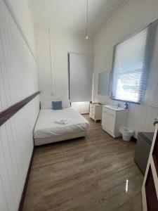 Habitación pequeña con cama, escritorio y lavabo. en The Australian Hotel, en Gympie