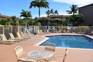 a swimming pool with chairs and a table and a table and chairs at Pacific Shores B303 in Kihei