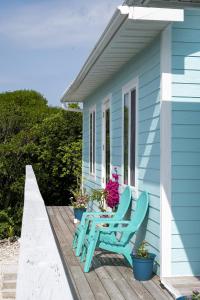 a blue house with two chairs on a deck at Flipper Refuge cottage in Governorʼs Harbour