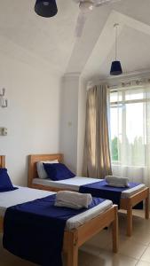 a bedroom with two beds with blue sheets and a window at Selah Holiday Apartment at Sebuleni Nyali in Mombasa