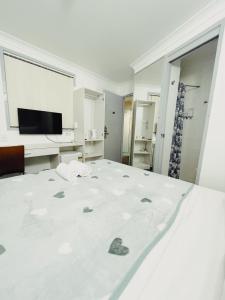 a white bedroom with a bed and a television at Turbot House Hotel in Brisbane