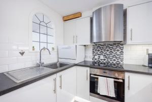 a kitchen with white cabinets and a sink at Canary Wharf Apartments By Austin David in London +17 photos