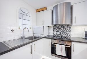 a kitchen with white cabinets and a sink at Canary Wharf Apartments By Austin David in London