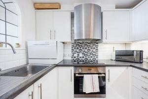 a white kitchen with a sink and a stove at Canary Wharf Apartments By Austin David in London