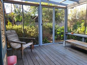 a screened in porch with a bench and windows at The Dunes - King Studio - 50m from Scamander Beach in Scamander