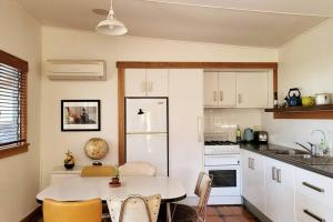 a kitchen with a table and a white refrigerator at The Dunes - King Studio - 50m from Scamander Beach in Scamander