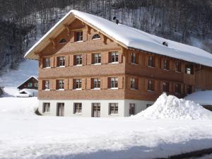 een gebouw bedekt met sneeuw met een berg sneeuw bij Haus Schwendinger in Mellau