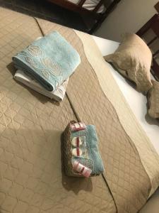 a bed with two towels and a pair of gloves at Hospedagem Econômica By Bia in Penha