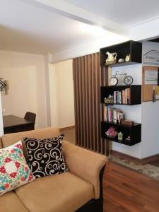 a living room with a couch and a book shelf at Hermosa y confortable suite in Quito