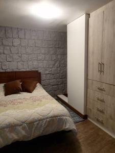 a bedroom with a bed and a brick wall at Hermosa y confortable suite in Quito