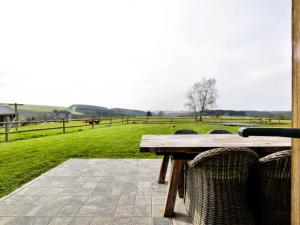 een picknicktafel op een patio met uitzicht op een veld bij Tranquil Holiday Home in Mont with bubble bath in Mont-lès-Houffalize