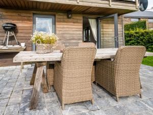 een houten tafel met rieten stoelen op een patio bij Tranquil Holiday Home in Mont with bubble bath in Mont-lès-Houffalize