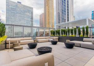 a rooftop patio with couches and tables and buildings at Luxury Gold Coast Home w/ Rooftop Pool & Gym in Chicago
