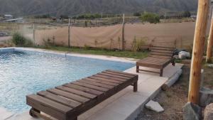 two wooden benches sitting next to a swimming pool at El Rincon in Cacheuta