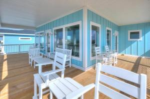 een kamer met witte stoelen en tafels op een terras bij Ocean Peek in Oak Island