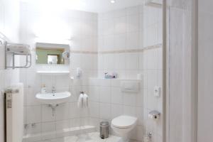 a white bathroom with a toilet and a sink at Parkhotel del Mar in Sassnitz +57 photos