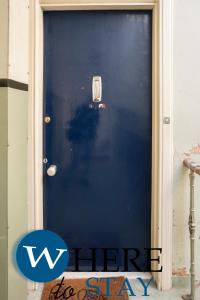 uma porta azul com um sinal que diz aqui fique em Charming 2 bedroom apartment in Gorgie em Edimburgo
