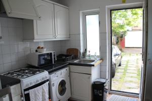 a kitchen with a sink and a washing machine at Cozy light single bedroom in Edgware