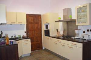 Una cocina con gabinetes blancos y una encimera negra. en Pavillon zen, en Petit-Bourg