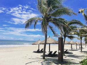 a beach with chairs and palm trees and the ocean at Moc Son Apartment - Attractive price for week and month stay in Da Nang
