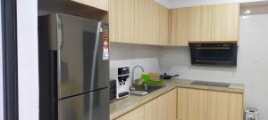 La cuisine est équipée d'un réfrigérateur en acier inoxydable et d'un four micro-ondes. dans l'établissement Sunsky Condominium Homestay, à Miri