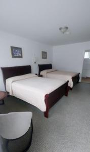 a hotel room with two beds and a chair at White Fang Motel in Wawa