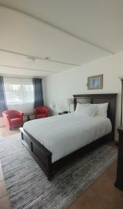 Un dormitorio con una cama grande y una silla roja. en White Fang Motel, en Wawa