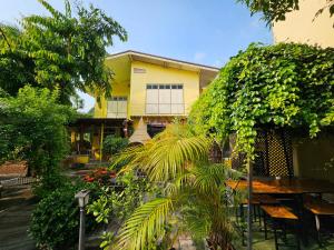 a yellow building with a table and some plants at SuanTung Coffee & Guesthouse in Chiang Rai