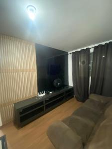 ein Wohnzimmer mit einem Sofa und einem TV in der Unterkunft Millennium Residence in Juiz de Fora